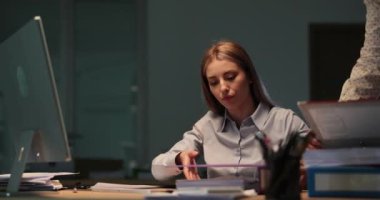 İş arkadaşı, iş arkadaşına gece geç saatlerde ofis odasında yeni dosyalar veriyor. Ekip, şirketteki son teslim tarihi nedeniyle projeye devam ediyor.