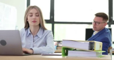 Adam işyerinde oturan kadına evrakları gösteriyor. İş arkadaşları mali raporu tartıştılar. İş anlaşması için belge hazırlıyorlar.