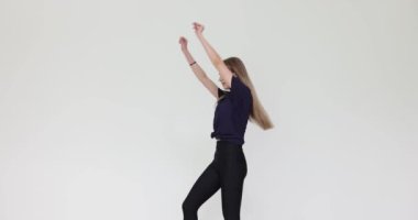 Sportif genç kadın beyaz arka planda dans unsuru gösteriyor. Sarışın kadın zarif bir şekilde stüdyodaki gösteriye hazırlanıyor.