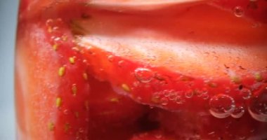 Şeffaf kavanozda, içinde şeker olan çilek dilimleri. Sağlıklı malzemelerden tatlı reçel yapmaya uygun lezzetli kırmızı meyveler.