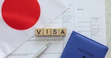 Pasaport ve Japon bayrağı yakınındaki masada Visa etiketli küp. Vize alma ve Japonya 'ya seyahat hazırlığı sürecini vurgula