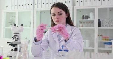 Esmer genç kadın bilim adamı test tüpüne pamuk çubuğu sokuyor. Deneyimli araştırmacı yaklaşan yavaş çekim analizi için örnek toplar
