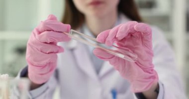 Genç araştırmacı kadın, pamuklu çubuğu test tüpüne sokuyor. Profesyonel bilim adamı yavaş çekim testleri için örnek topluyor.
