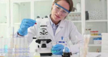 Genç bilim kadını mikroskop altında inceleme için örnek hazırlıyor. Araştırmacı yavaş çekim için sıvıyı transfer etmek için pipette kullanır