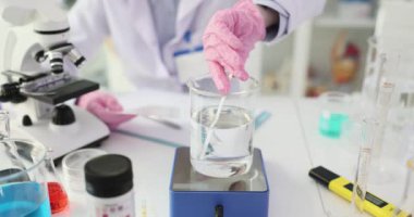 Bilim adamı laboratuardaki PH test bantlarını kullanarak su örneğini analiz ediyor. Kimyager, iş yerindeki tabloyla kağıt üzerindeki renk kalıbını karşılaştırır