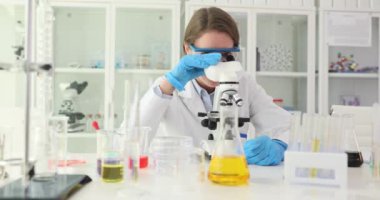 Gülümseyen bilim adamı tıbbi laboratuvarda mikroskopla çalışıyor. Kimya laboratuvarında modern ekipmanlarla çalışan profesyonel biyokimyacı.