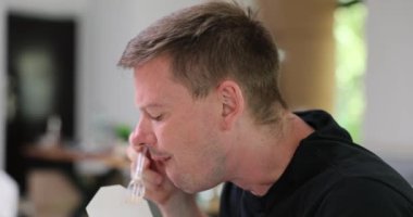 Çalışan adam öğle yemeği arasında ofiste yemek yer. Genç işçi iş yerinde ağır çekimde lezzetli atıştırmalıkların tadını çıkarıyor.