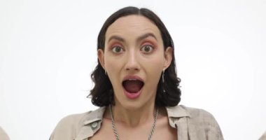 Stüdyoda elleri beyaz arka planda olan genç bir kadın ağzını kapadığını gösteriyor. Duygusal bayan haberlerle heyecan yaşar.