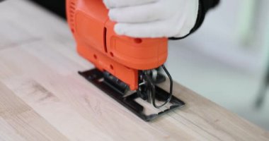 Eldivenli işçiler, atölyede tahta tahta kesen yapboz tutuyorlar. Çalışan sert yüzey ile başa çıkmak için özel aygıt kullanır