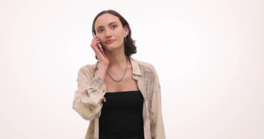 Mutlu yüz ifadesi olan genç bir kadın telefonla arıyor. Kısa saçlı bir kadın, beyaz duvara karşı arkadaşıyla konuşurken eğleniyor.