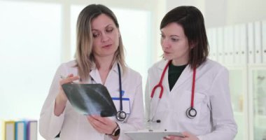 Yoğunlaşmış terapistler klinikte hastanın göğüs röntgeni görüntüsünü tartışıyor. Doktorlar akciğer hastalıklarının gelişimini analiz ediyor.
