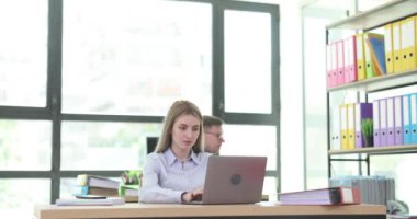 Erkek müdür, masada dizüstü bilgisayarda çalışan genç bayan çalışanın telefonuyla fotoğraf çekiyor. Adam, meslektaşlarını gözetleyen iş şirketinin verilerini çalıyor.