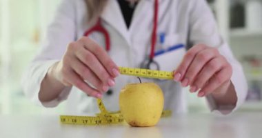 Doktor sarı elma ve bant sağlıklı yeme ve kilo verme konseptini ölçer. Kadın beslenme uzmanı randevuda taze meyve gösteriyor