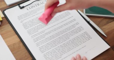 Kadın sekreter, ahşap masada yeşil mürekkeple kontrat imzalıyor. Şirket çalışanı sözleşmeyi ofis ortamında yasal olarak onaylanmış olarak işaretledi