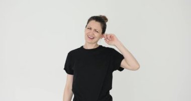 Kadın kulak ağrısından muzdarip ve beyaz arka planda huzursuzluk yaşıyor. Dişi, ağrılı hisleri azaltmak için ağrıyan kulağa masaj yapmaya çalışır.