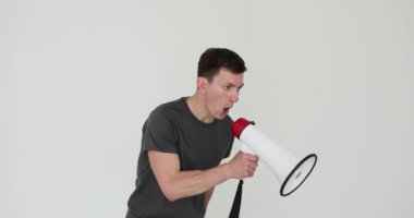 Kızgın fitness koçu beyaz arka plandaki eğitimde megafon kullanarak bağırıyor. Öfkeli yüz ifadesi olan katı adam olumsuz duygularını ifade eder.