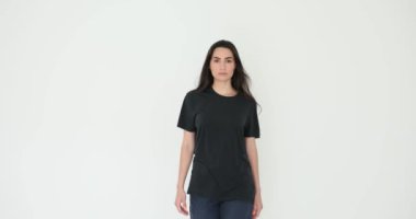 Çekici genç bir kadın beyaz arka planda rahatça poz veriyor. Gayri resmi siyah giysili esmer kadın manken defileden önce prova yapıyor.