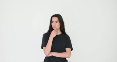 Genç bir kadın, beyaz arka planda yüz ifadeleri ve jestlerle kaygı gösterir. Siyah tişörtlü gergin kadın takıntılı düşüncelerle uğraşıyor.