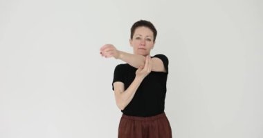 Kadın vücudunun üst kısmını gösteriyor ve beyaz arka planda dirsek ve ön kolları hedef alıyor. Bayan ortak sağlık için hareket esnekliğini artırıyor