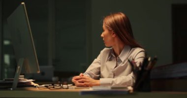Kadın tezgahtar şirket ofisinin pencerelerinin arkasındaki yıldırımlara tepki göstererek başını sallıyor. Gece geç saatlere kadar çalışmaktan yorgun düşmüş genç bir çalışan.