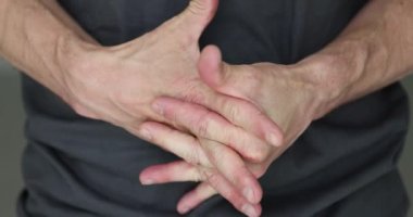 Adam heyecanla el ele tutuşup yavaş çekimde heyecan yaşıyor. Erkek, ofiste iş görüşmesini beklerken gözle görülür bir şekilde olumsuz duygular yaşıyor.