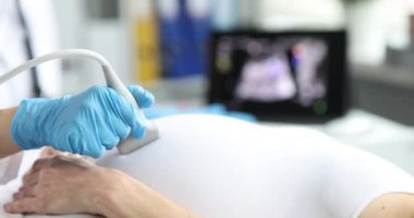 Doktor, hastanede hamile kadını muayene eden bir transformatör tutuyor. Sağlık durumunu kontrol etmek için modern sonografi cihazlarıyla doğum öncesi kontroller