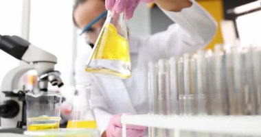 Scientist conducts chemical experiment in flask with oil. Toxic and poisonous solvent concept