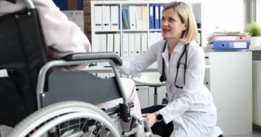 Doktor tekerlekli sandalyedeki hastanın dizine çekiç darbesi uyguluyor. Engelli ve kas düzelmesi için rehabilitasyon kliniği diz osteoartrit yenileme kavramı
