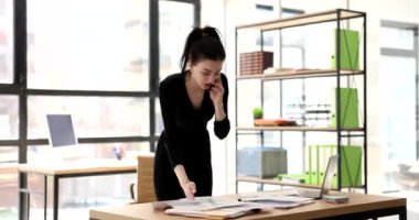 Stresli iş kadını memnun olmayan müşteriyle telefonda konuşuyor ve sorunları uzaktan çözüyor. Yönetici işle ilgili şikayetleri dinliyor ve mali rapora öfkeleniyor