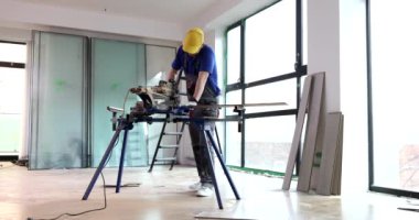 İşçi testereyle parke yapmak için tahta keser. İnşaatçı zemin kaplama malzemesi hazırlar