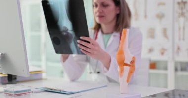 Doktor, klinikteki hastanın dizinin röntgenini inceliyor. Menisküs yırtığı semptomlara ve tedaviye neden olur