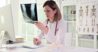 Doktor kırık ayaklı röntgene bakıyor. Kaza sigortası kavramı