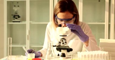 Bilim adamı biyoloğu araştırma laboratuarındaki mikroskoba bakıyor. Bilim eğitimi ve kimyasal araştırma