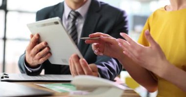 Dijital tablet kullanarak konuşan iş arkadaşları ofis masasında oturuyorlar. Teknik cihaz ve kurumsal teknoloji iş uygulamaları