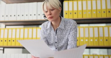 Müşteri hizmetleri çalışanlarını ara, belgelerini tutsunlar ve müşterilerle iletişim kursunlar. Kulaklık takmış bir kız, potansiyel müşteriyle konuşuyor.