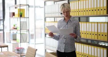 Çağrı Merkezi müşteri hizmetleri çalışanı iş ortağıyla iletişim kurmak için evrakları tutuyor. Kağıt tutan ve müşteri ya da müşteriyle konuşan bir yönetici