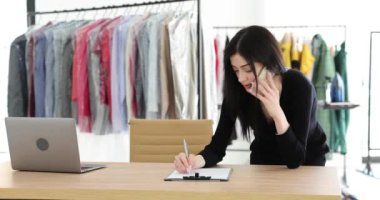 Çamaşırhane çalışanı telefonda konuşuyor ve emir yazıyor. Müdür kuru temizleme kıyafetlerini kontrol ediyor.