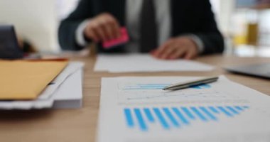 İş yerinde elinde analitik kağıtlarla oturan erkek ofis çalışanı damgaları. Resmi takım elbise yöneticisi yatırımcılara belge hazırlamakta zorlanıyor