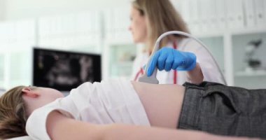 Nazik kadın doktor, ultrason cihazıyla mide hastalığı olan küçük bir kızı muayene ediyor. Dikkatli kadın yavaş çekimde hastanın iç karın görüntüsüne bakıyor.