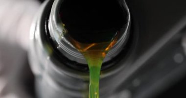Kişi dikkatli bir şekilde araba motor yağını plastik kutudan motor bölmesine döker. Tamirci siyah arka planda araba tamir ediyor. Araba servisi.