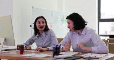 Çalışanlardan birkaçı müşteriyle iyi anlaşmanın getirdiği gelirle seviniyor. Genç adam ve kadın gülümseyip el sallayarak ofiste ağır çekimde oturuyor.