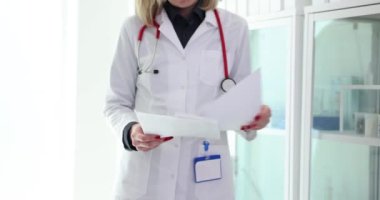 İş üniformalı kadın doktor hastane öncülüğündeki hasta verilerini inceliyor. Kadın uzman, iş yerindeki hasta tıbbi geçmişi hakkında bilgi okuyor