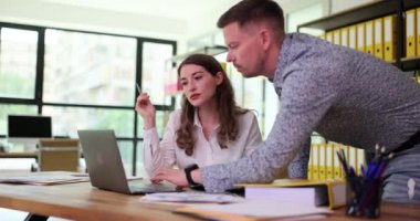 Erkek iş arkadaşı, iş yerinin yanında duran yeni bilgisayar programını nasıl kullanacağını gösteriyor. Şirket çalışanları arasında iyi ilişkiler. Karşılıklı yardım