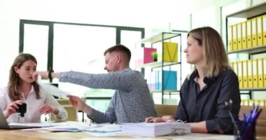 Erkek işçi, ahşap masada otururken damgalamak için meslektaşına kağıt belge verir. Yönetici ofis çalışanları patrona gayret ve sıkı çalışma gösteriyor