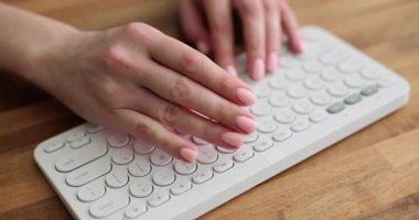 Çıplak manikürlü bir kadın eli, tahta masada yatan beyaz klavyeye kırmızı zarlar koyar. Taşınabilir tuş takımında eşit noktalar olan şeffaf kırmızı fildişleri. Talih konsepti