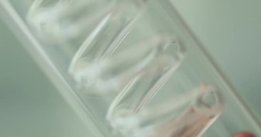 Kırmızı sıvı, laboratuvar ekipmanlarıyla spiral plastik tüpten yukarı akıyor. Kimyasal deney sırasında yavaş çekimde sıvı. Modern laboratuvarda kimyasal özelliklerin incelenmesi