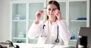 Steteskopta uzman bir uzman tıbbi tesiste randevu sırasında gözlük takıyor. Kadın doktor hastalarını ağır çekimde kabul eder.