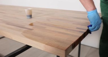 Adam cilalanmış ofis masası yüzeyini cila beziyle cilalıyor. Kauçuk eldivenli marangoz, ahşap işleri yavaş çekimde parlatma kavramı.