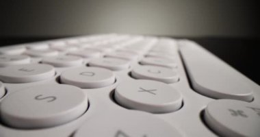 Light modern keyboard with round keys on black surface. Small neat keyboard for typing long texts and working stands under mild light in studio