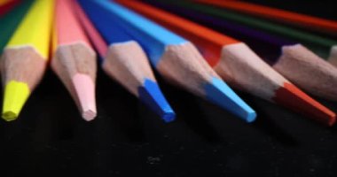 Sharpened multi-colored pencil tips lined up on black surface. Stationery made for kids and adults for drawing and studying purposes. Tool for artist